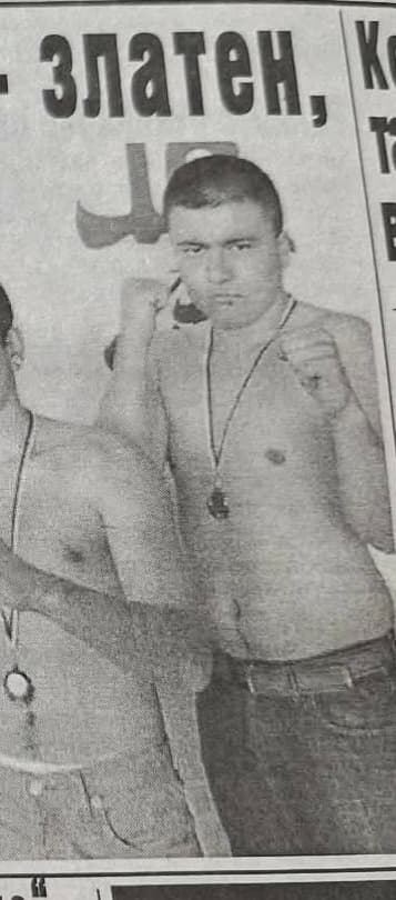 Shirtless young man in a boxing stance wearing a medal in a vintage newspaper.