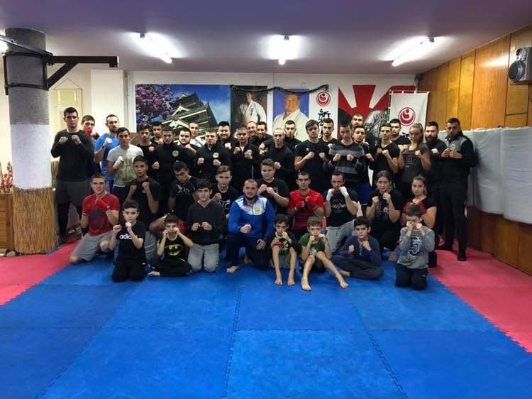 Large group of martial arts students and instructors posing for a photo in a dojo.